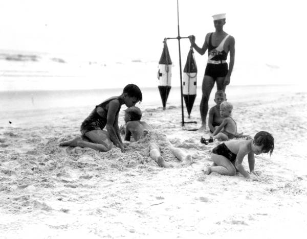 Children on the beach watched by a lifeguard.