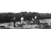 Loading wheelbarrows with sandy clay from the river