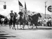 Rodeo performers carry the flag down the street during a parade - New Smyrna Beach, Florida .