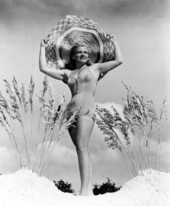 Adeline Finke of Miami, Florida, posing with large hat and sea oats on the beach.