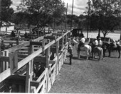 Unidentified man checks the fences while horseman waits - Bonifay, Florida