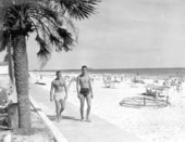 View of a couple of fellows walking along the beach.