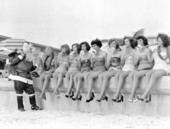 Santa Claus handing out treats to nine young women on the beach - Saint Petersburg, Florida