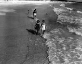 Young women walk together through the water.