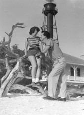 Honeymooners Lyn and Jim Agramonte visit the lighthouse behind a house - Sanibel Island, Florida.