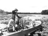Miss Azilee Nesmith watches Harry Daniels holding a string of black bass caught at Little Lake George - Welaka, Florida.