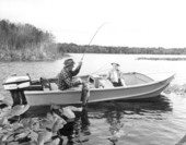 Miss Azilee Nesmith watches Harry Daniels landing a black bass caught at Little Lake George - Welaka, Florida.