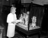 A staff memberem looking at Dresden porcelain figures at the Lightner Museum - Saint Augustine, Florida
