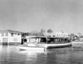 Small boat glides by a larger tour boat at dock