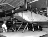 Men looking at a 1918 Curtiss N-9H Navy trainer at the Naval Aviation museum in Pensacola.