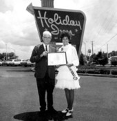 Miss Airlines International, Jean Hartnett, receiving an award in front of a Holiday Inn sign