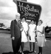Miss Airlines International, Jean Hartnett, in front of a Holiday Inn sign with a man and two women
