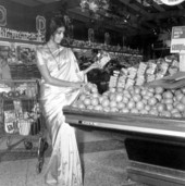 Woman dressed in a sari examines fruit in the grocery storeTallahassee, Florida