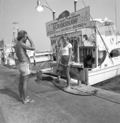 A man taking a picture for a young woman in front of a charter boat - Destin, Florida