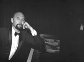 Portrait of concert pianist Yehuda Guttman leaning against piano at the Red Barn Theatre - Key West, Florida.