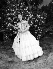 Miss America 1954, Evelyn Ay (later Sempier), posing with antique clothing in front of an orange tree in Winter Haven.