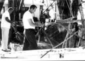 Shrimp boat Captain mending a net on board his shrimp boat while docked at the Key West Bight, Key West, FL..