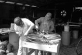 Wheelwright and coach maker John Luther and his apprentice Raymond Richardson working with a wagon wheel - McAlpin, Florida