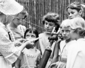 Jessie Coker demonstrating spinning to girls at the 1959 Florida Folk Festival - White Springs, Florida