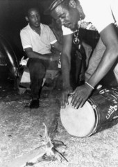 Member of Haitian Rara band Konbo Guinyn tunes his conga drum by heating the head - Miami, Florida.