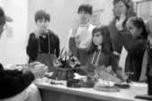 Unidentified man showing wildlife carvings to school group