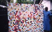 Mrs. Josephine Burns standing with her yoyo quilt in Eatonville, Florida.