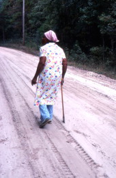Basket maker Lucreaty Clark walking down a dirt road