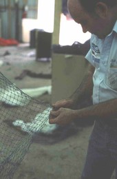 Net maker Billy Burbank II beginning repair of a torn fishing net - Fernandina Beach, Florida