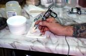 Tattoo artist Jon Fort dipping the needle into ink - Pensacola, Florida.