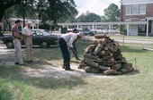 Men getting the firewood and iron ring used to place forks for roasting mullet ready - Monticello, Florida