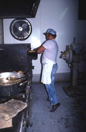 Worker at Suzanne's Foods putting knishes into the oven - Miami, Florida.