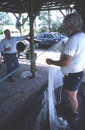 Costa Buzier hanging a trawl net and sewing webbing while Marcus Hepburn looks on - Apalachicola, Florida.