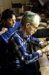 Leather worker Bob Dellis works while apprentice Kitt Maynard looks on - Okeechobee, Florida