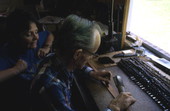 Leather worker Bob Dellis works while apprentice Kitt Maynard looks on - Okeechobee, Florida