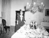 Margaret Hood next to dining room table with tableware and silverware sets on display at Goodwood
