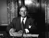 Governor Fuller Warren signing document at his desk.