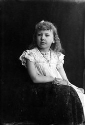 Seated portrait of Macintosh girl, hair in ringlets and large cameo at neckline.