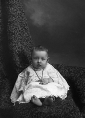 Infant holding a cross necklace.