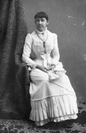 Unidentified woman in tiered dress, holding a fan.