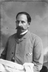 Man with wispy goatee and curly mustache.