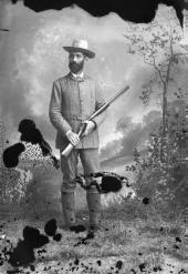Man in hunting clothes, holding a rifle.