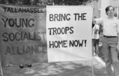 FSU student standing next to a Young Socialist Alliance political banner at anti-war demonstration.