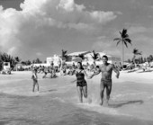Lifeguard and girl running into the water outside the municipal casino on Lido Beach, Florida.