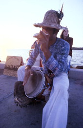Musician blowing conch shell while beating drum during the Sunset Celebration at Mallory Square in Key West.