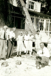 Koreshans looking at coconuts next to the Koreshan Unity's "Rising Tide Cottage" at Fort Myers Beach, Florida.