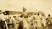 Postcard showing crowd gathered around an airplane.