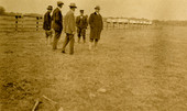 Postcard showing a group of men standing in a field.