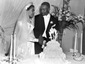 Newly married African American couple cutting cake