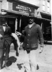 Man holding up bass fish in front of McNally's grocery store - Madison County, Florida