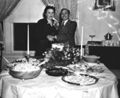 Celia and Joe Meltzer standing behind a table full of food
